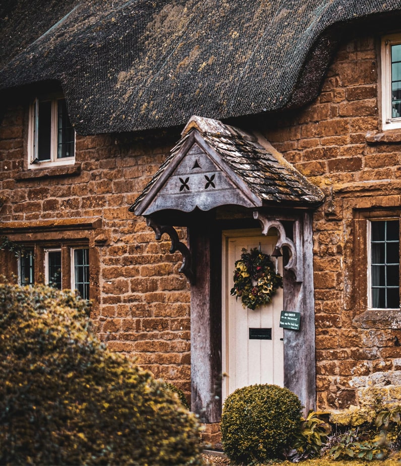 Christmas wreath on traditional front door of a thatched roof Cotswold holiday home