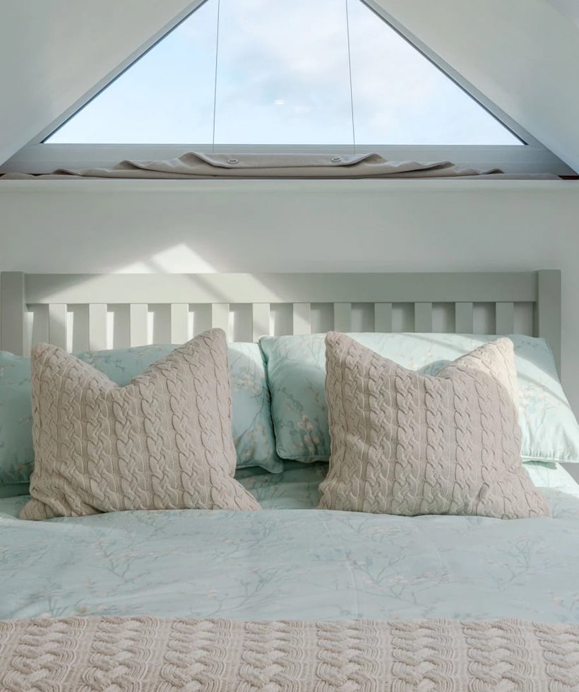 A relaxed bedroom with double bed and triangle window